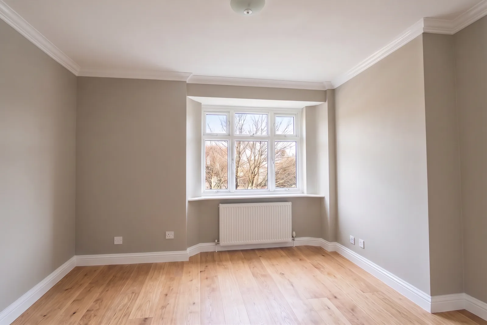 The same room after full redecoration, fresh walls, new skirting and a wood floor